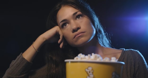 A close-up of a person looking thoughtfully at a movie screen, reflecting the emotions of the film back onto them. The lighting is soft, highlighting the viewer's expression and the impact the film is having on them. The background is blurred, emphasizing the connection between the viewer and the screen.