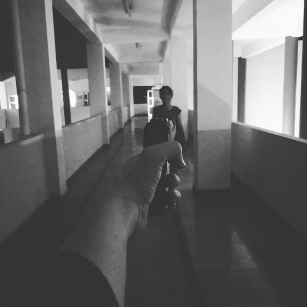 A black-and-white image showing a chaotic scene inside a mental institution, with patients wandering around in various states of undress and distress.