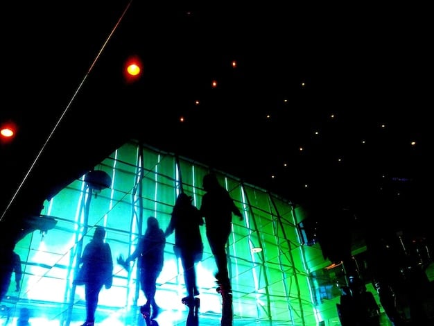 A high-energy concert scene of a popular K-Pop group performing in a large US stadium, packed with fans holding light sticks. Capture the excitement and vibrant atmosphere of the event, emphasizing the massive audience and the group's dynamic stage presence.
