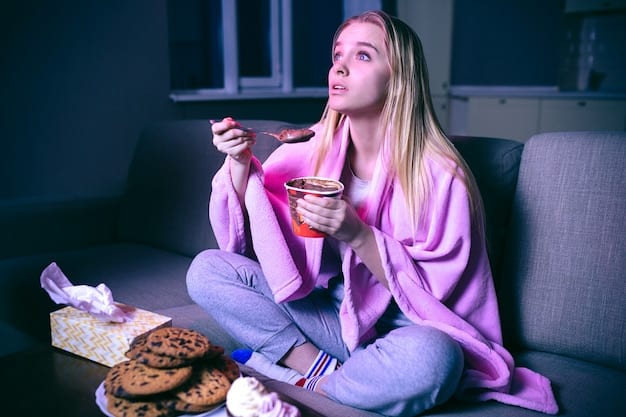 A person sitting comfortably on their couch at home, surrounded by snacks, watching a movie on a large screen TV with dimmed lights.