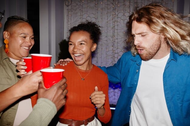A diverse group of people enjoying snacks and drinks while watching a movie together in a cinema, with focus on their excited and engaged expressions.