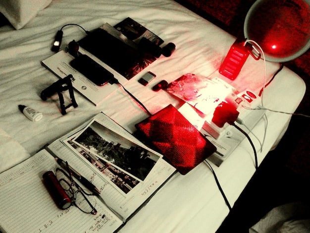 A photo showcasing diverse true crime media, including books, podcasts on a smartphone, and a documentary playing on a laptop, with various news articles scattered around, symbolizing the pervasiveness of the genre in modern culture.