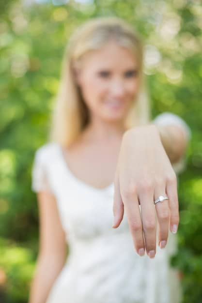 A close-up photo of Blake Lively's hand with her engagement ring and wedding band prominently displayed. The rings are sparkling and elegant, symbolizing her commitment to Ryan Reynolds. The background is blurred, keeping the focus solely on the jewelry.