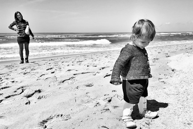 A candid black and white photo of children playing on a beach, symbolizing the family life at stake in the custody battle. The image is slightly blurred to protect their privacy.
