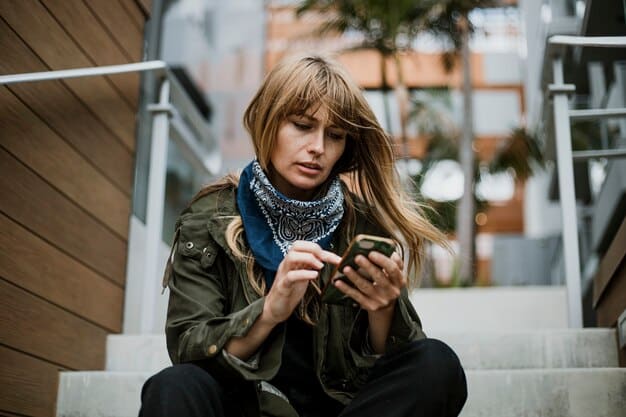 A candid photo of Hailey Bieber looking slightly stressed while talking on the phone in public. She is wearing casual attire and appears to be in a busy urban setting.