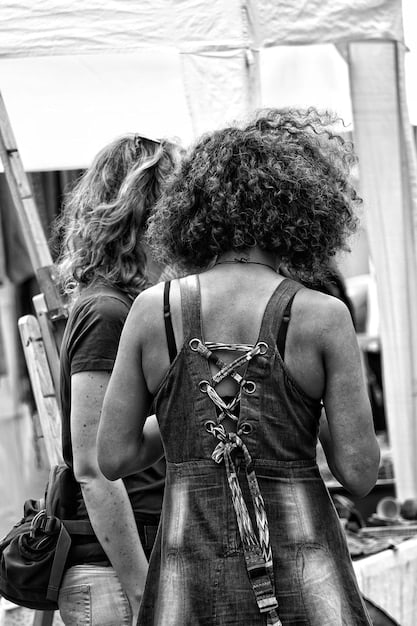 A black and white photo of Beyoncé and Jay-Z holding hands, walking through a crowd of paparazzi. They both have serious expressions, but their hands are clasped tightly. The image represents their unity amidst public scrutiny.