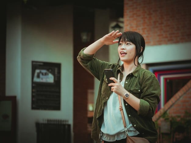 A candid shot of Jun Ji-hyun laughing while filming a scene for a K-drama. She's wearing stylish clothing, and the image captures her energetic and charismatic personality on set. The scene is brightly lit, highlighting the cheerful atmosphere.