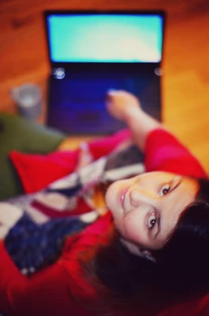 A close-up shot of a person watching a K-drama on a laptop, with a focus on the English subtitles at the bottom of the screen. The ambient light is soft, creating a cozy and immersive viewing experience.